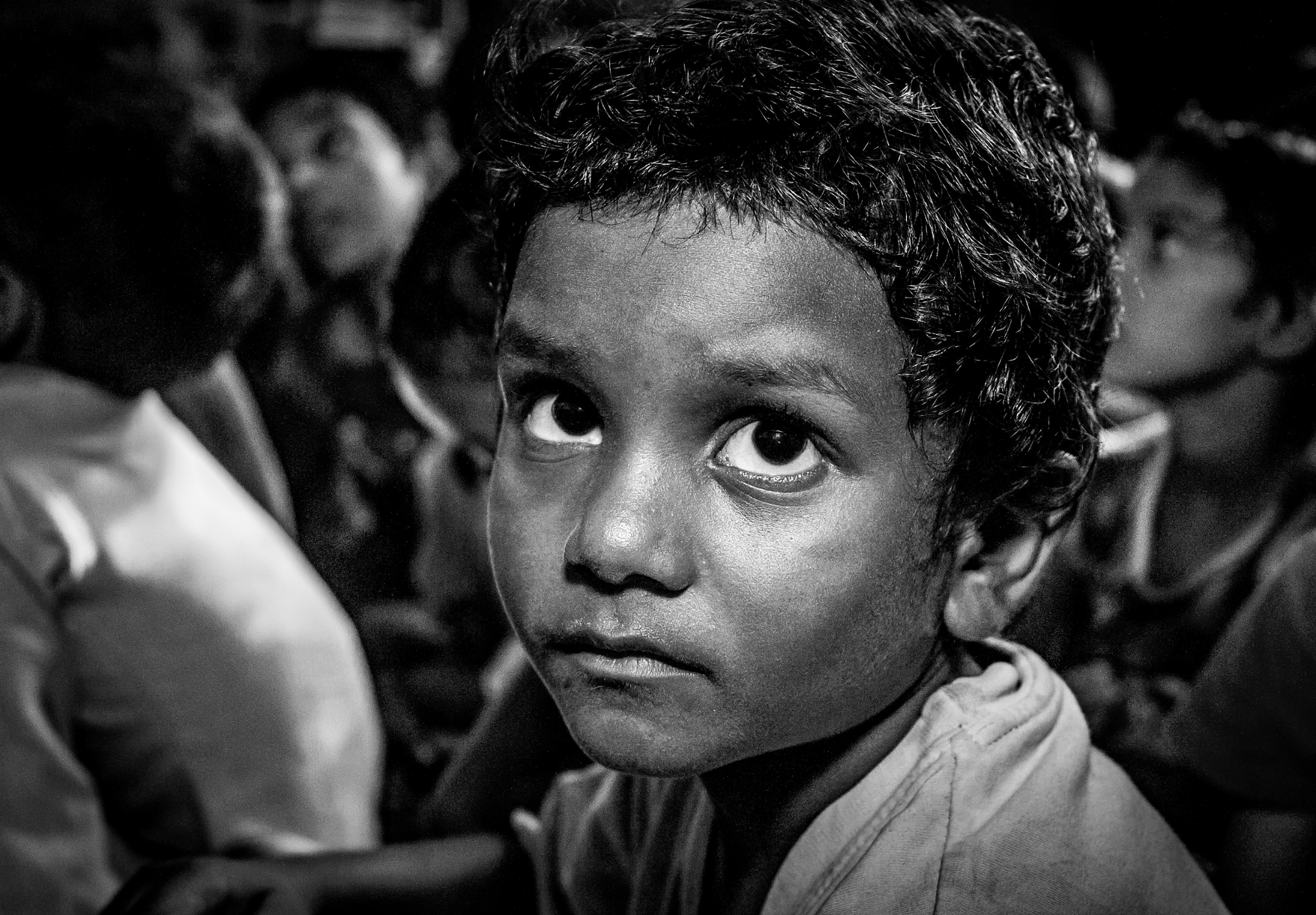 Black and white close portrait of a boy looking directly into the camera