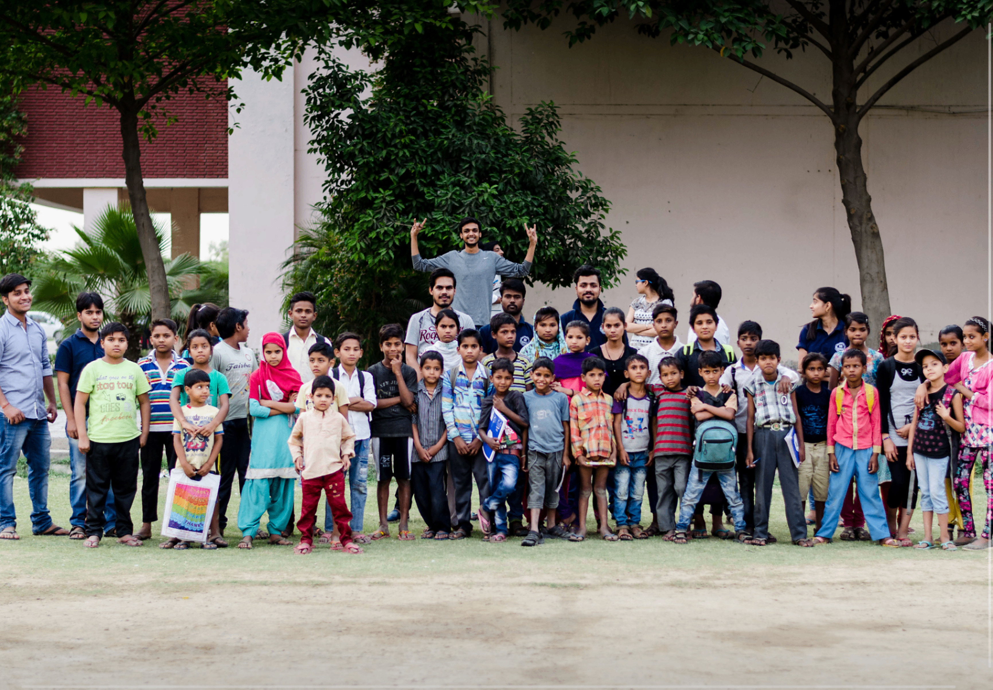 A large group of children and adults standing together outdoors with books and school materials