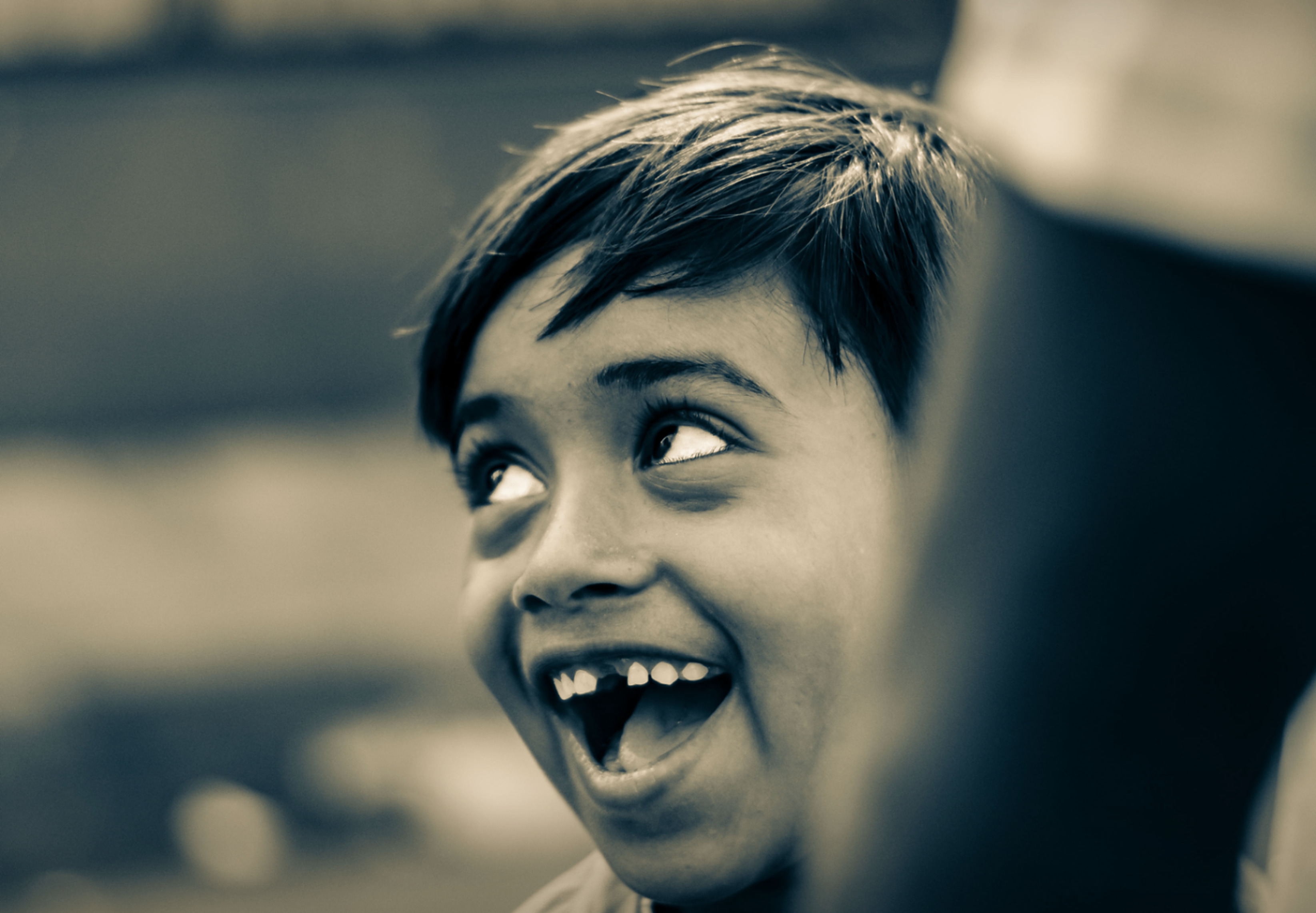 A laughing child mid-expression, toned monochrome photograph